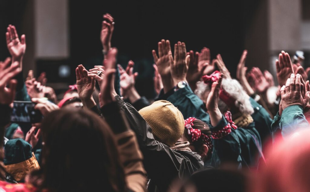 Folk rækker hånden op til et vælgermøde